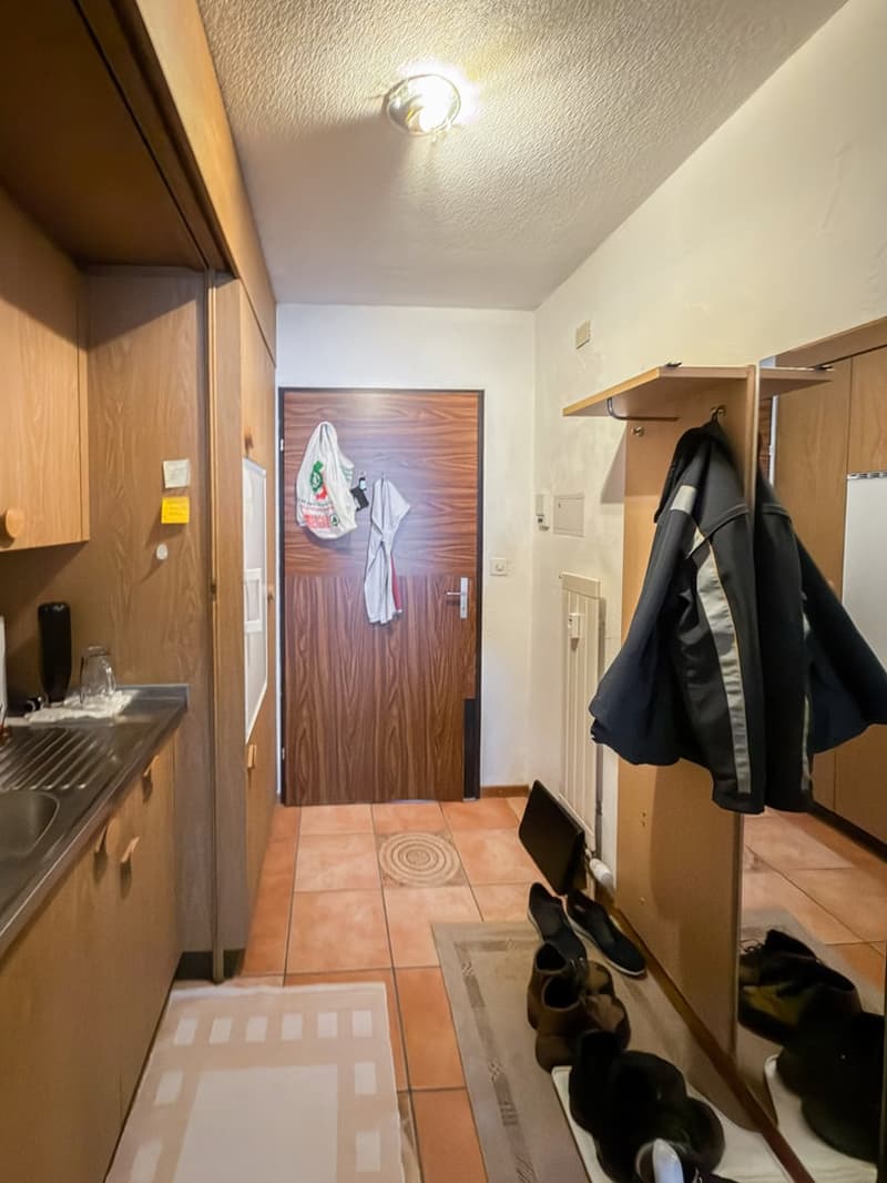 Entrance hall with cabinets, a sink, a door leading to a room, and a rack for shoes and coats.