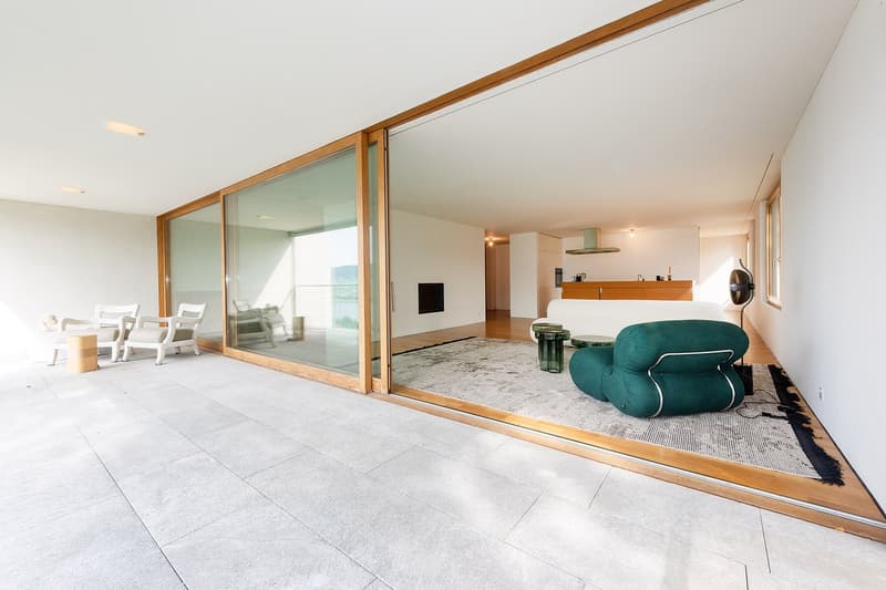 white floor, wooden doors, glass walls, balcony, outdoor table and chairs, green armchair