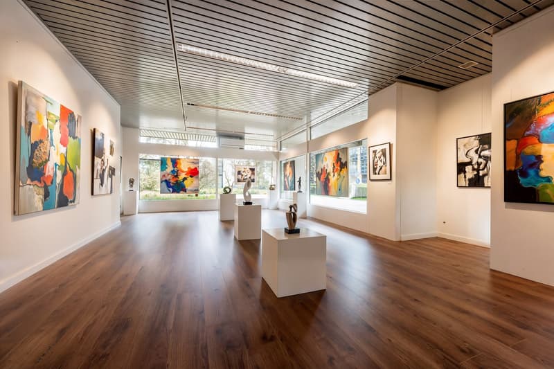 art gallery, wooden floor, white walls, large windows, modern art pieces, sculptures