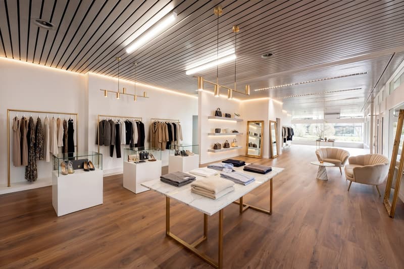 modern interior, wooden floor, white walls, clothing racks, display tables, mirrors, seating area