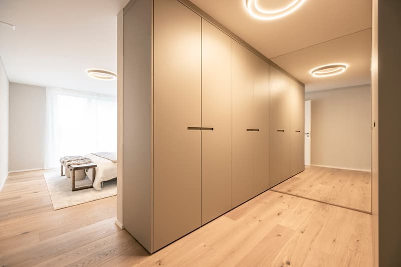 Spacious bedroom with built-in wardrobe, hardwood flooring, and modern lighting fixtures