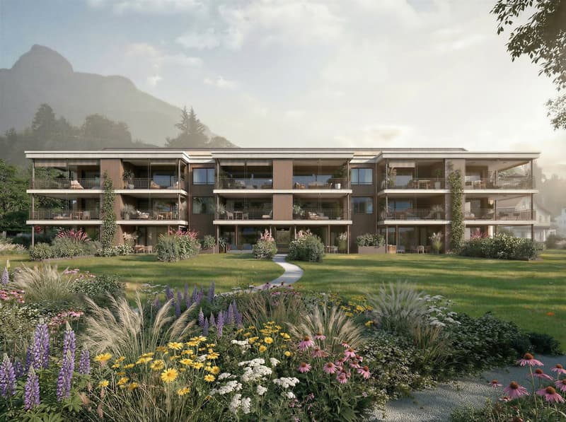Modern apartment building with balconies, nestled in a scenic location with mountains and greenery.