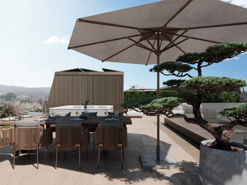 Outdoor dining area with a large umbrella, wooden table, chairs, and a potted tree. There is a hot tub in the background.