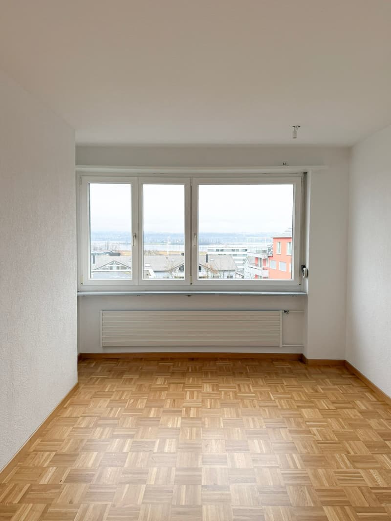 large window, wooden parquet floor, white walls, heater