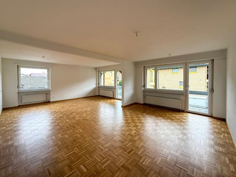 Large room with wooden floors, white walls, glass windows, sliding doors, large windows, balcony