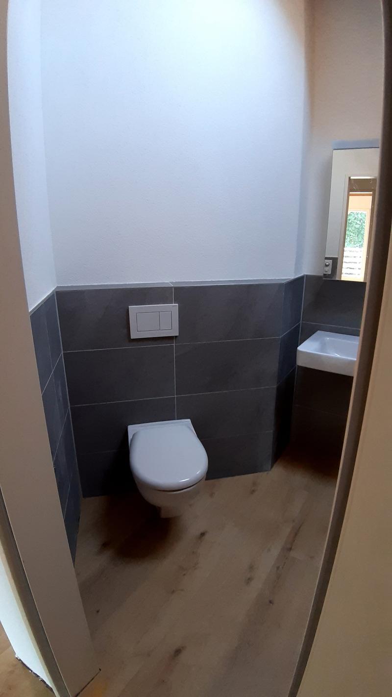 Bathroom with toilet, sink, and tiled walls