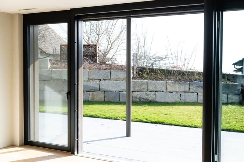 Sliding doors, glass wall, outdoor deck, grassy lawn, stone wall