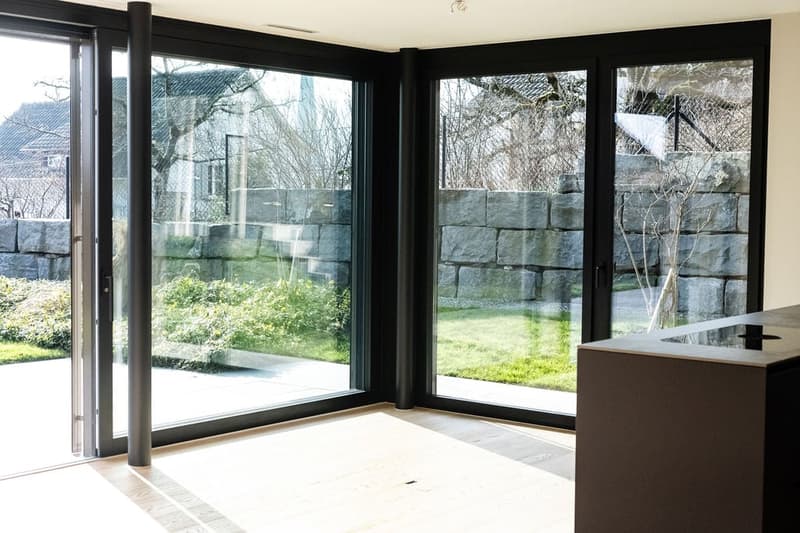 Sliding glass doors, white floor, green outdoor garden, stone wall