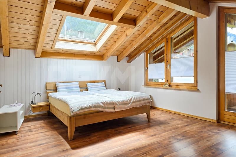 bedroom with wooden bed, wooden floor, wooden ceiling, skylight, windows, nightstands, lamp