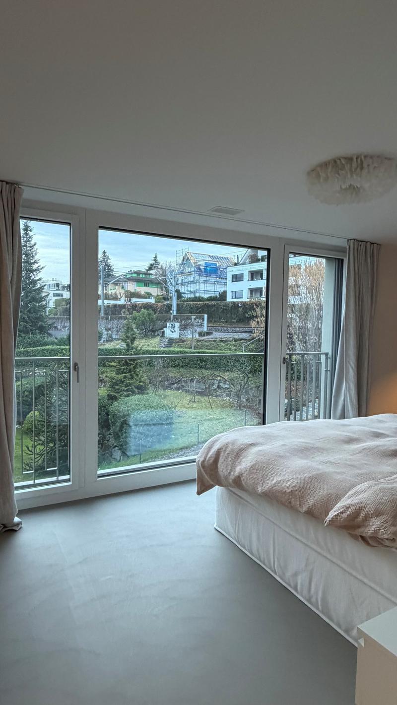 large bed, beige covers, floor balcony, big glass windows, metal fence, view of landscape