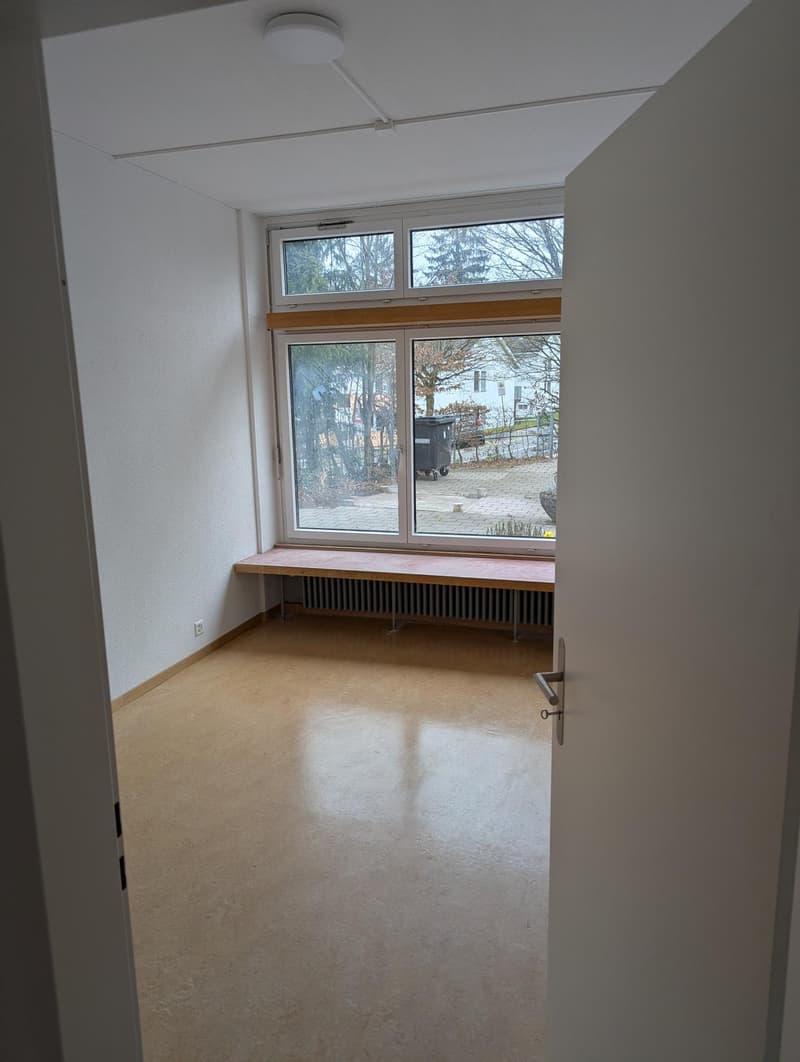 empty room, white walls, wooden bench, large window, radiator, tiled floor