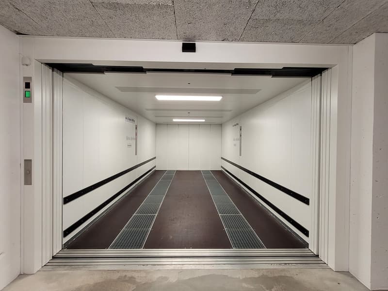 white walls, white ceiling, brown floor, steel grill, control panel, open entrance
