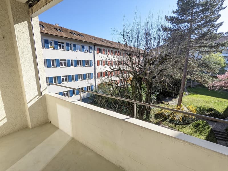 Balcony with railing, view of a building and garden