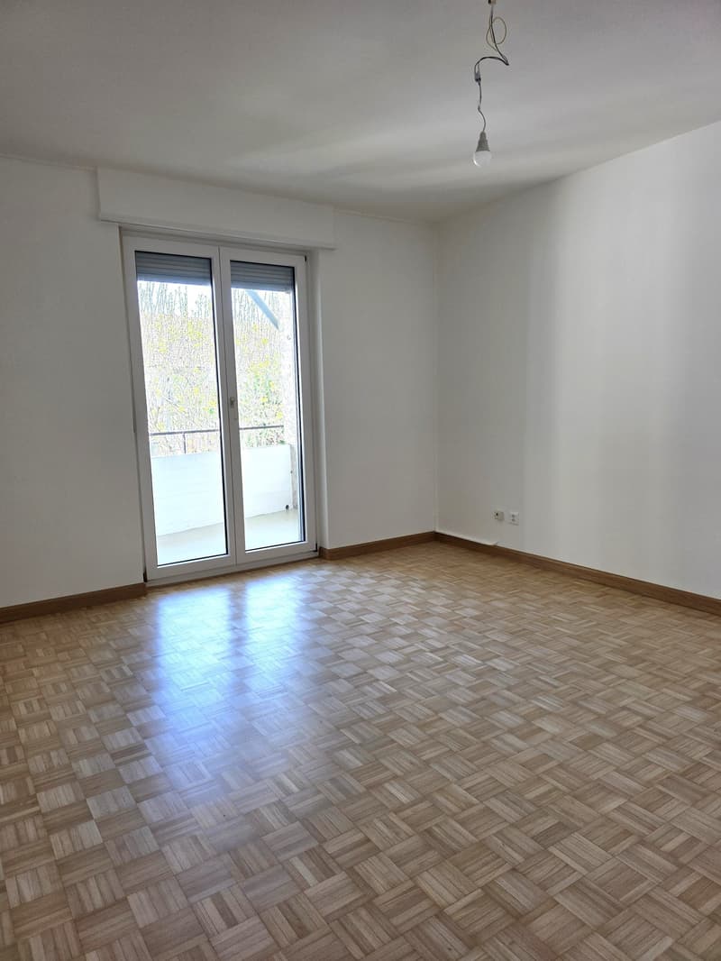empty room, wooden parquet floor, sliding glass doors, balcony, white walls, power outlet