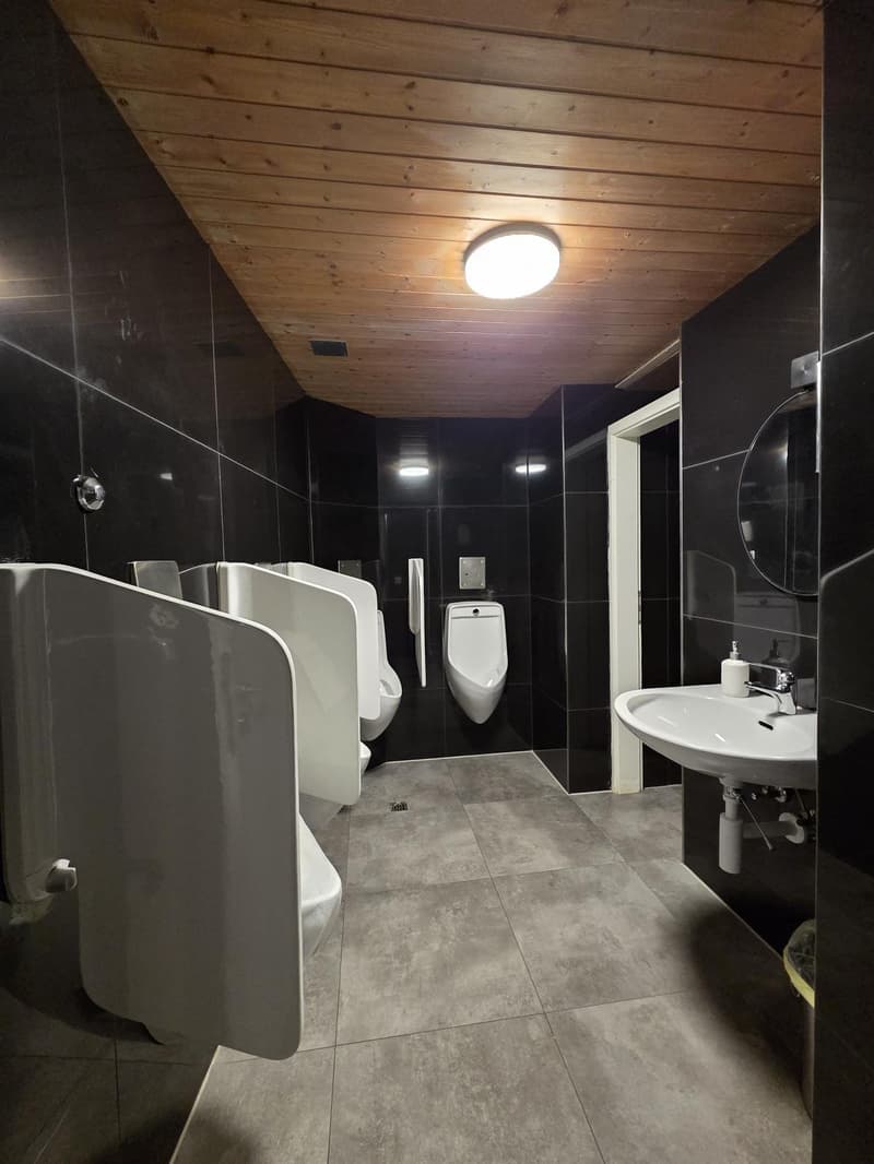 A bathroom with 4 urinals, a sink, and a mirror