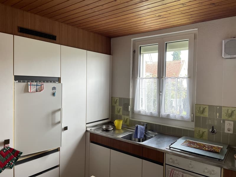 white cabinets, tiled backsplash, stainless steel sink, yellow cup, power outlet, view of the outside