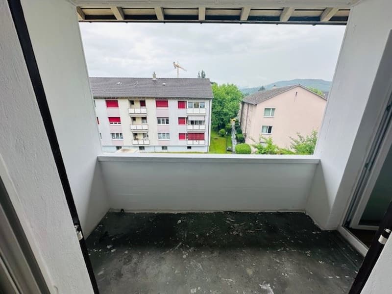 empty balcony with white walls, black floor, view of other buildings