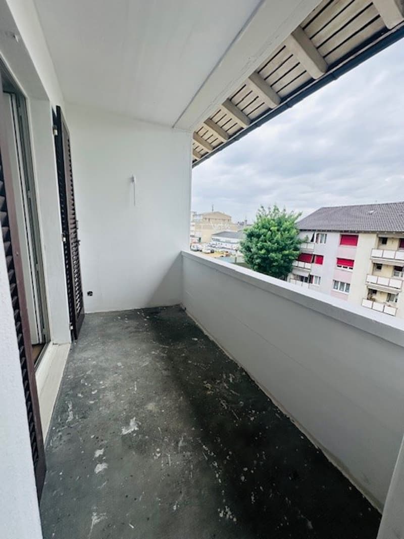 empty balcony with white walls, black floor, railings, and a view of the outside