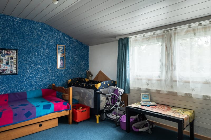 Children's room with wooden bed, crib, stroller, storage boxes, picture frame, window with curtains, blue carpet