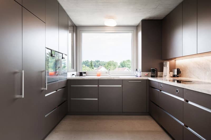 modern kitchen with large windows, marble countertops, modern appliances
