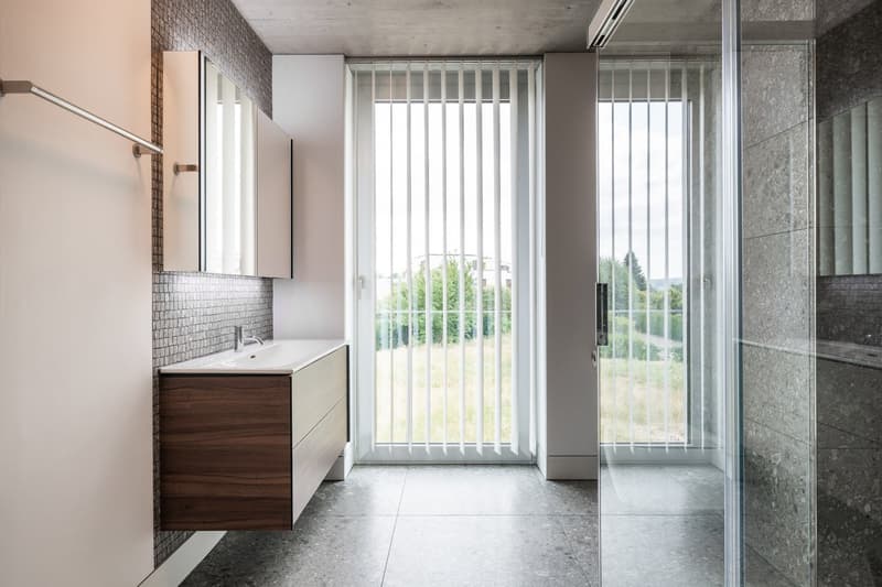 Sink, wooden cabinet, tile walls, large window with blinds, shower