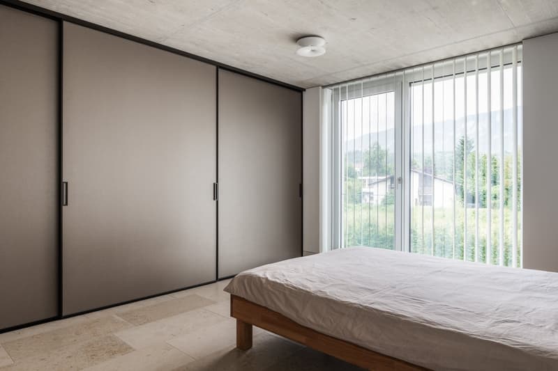 minimalist bedroom, wooden bed, large sliding glass doors, built-in wardrobes, tiled floor, white linen sheet