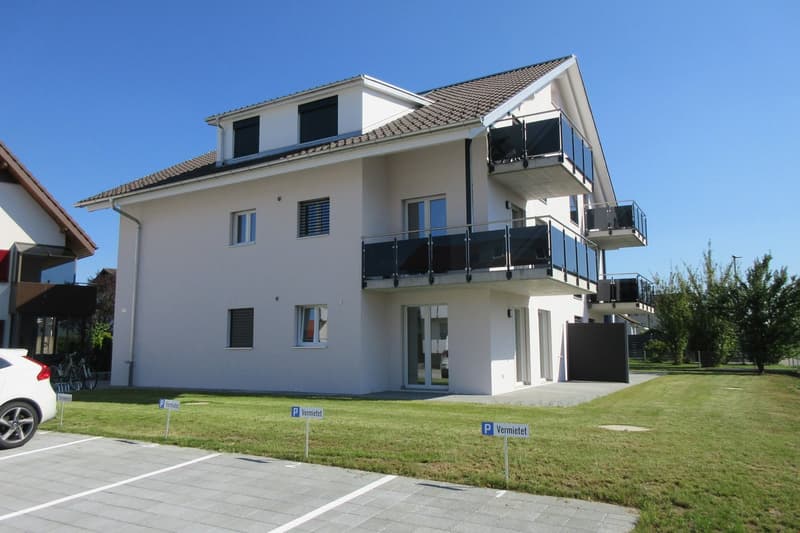 2 story house, white exterior, brown roof, glass doors, glass windows, balconies, parking area, lawn