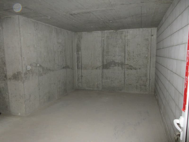 Empty room with concrete walls and floor, white brick wall on the right side