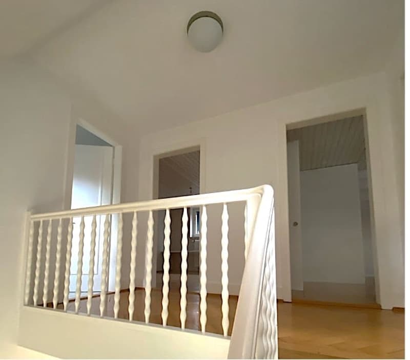 white walls, wooden floor, white railing, white doors, light fixture