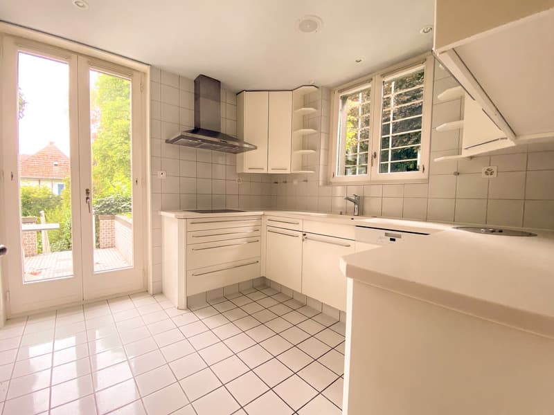 modern kitchen with white tiles, white cabinets, stainless steel appliances, double doors leading to a patio