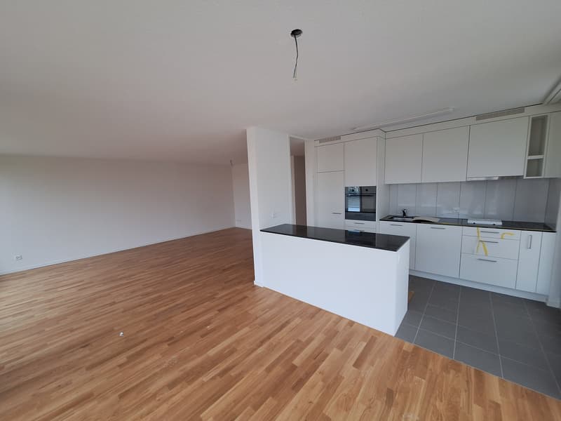 empty kitchen with white cabinets, black countertops, modern appliances, wooden floor
