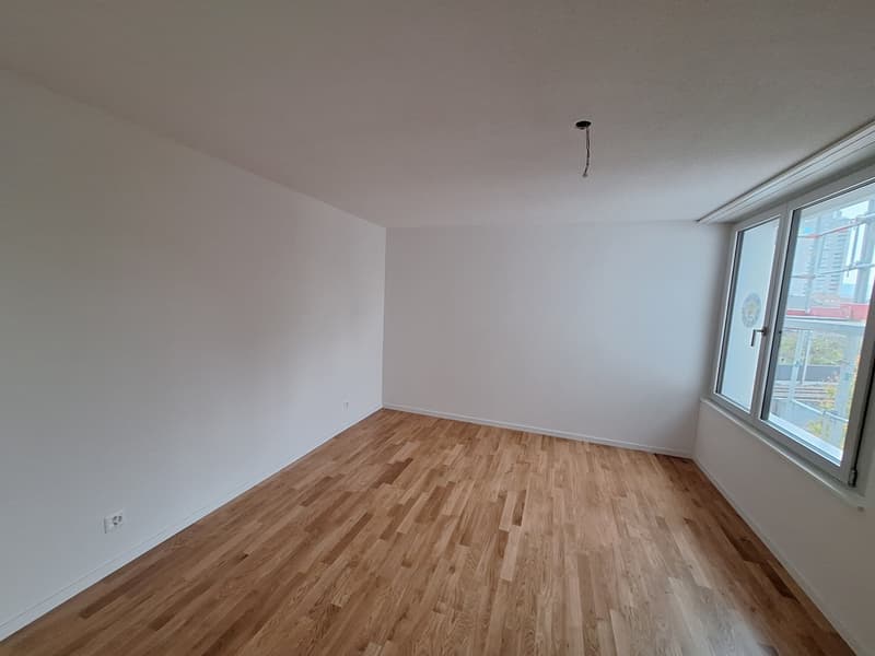 empty room, hardwood floors, white walls, a power outlet, a window, and an exterior view