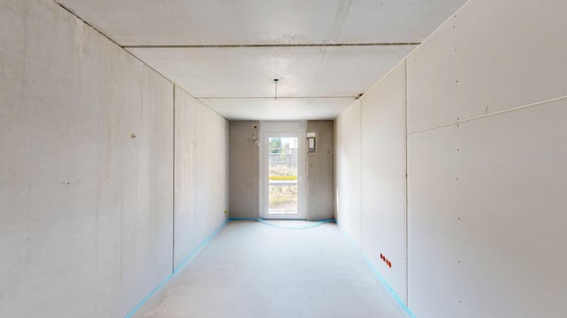A room with white walls and a concrete floor, appears to be under construction.