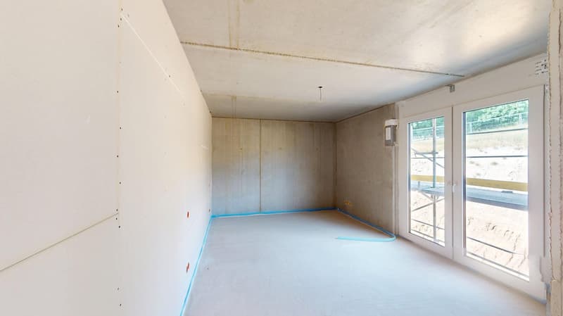 Empty room, white walls, concrete floor, glass doors, no furnishings, construction scaffolding visible outside