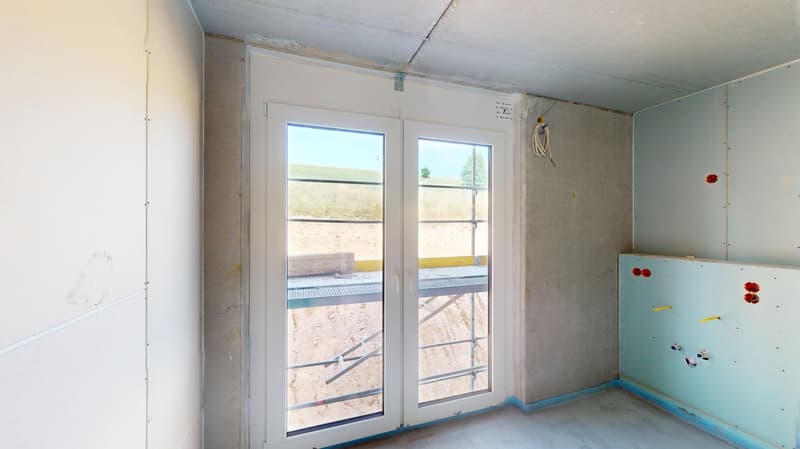 Room with unfinished interior, double doors, windows, exposed concrete, blue walls, electrical box, scaffolding