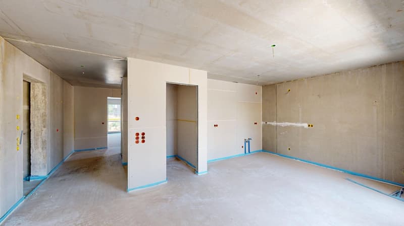 room with concrete walls, no windows, unfinished with gray drywall, blue border on edges, pipes on wall, no flooring