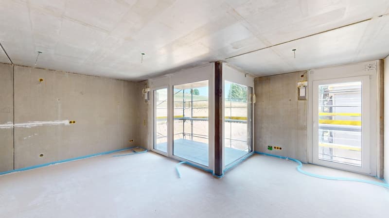 Empty room with unfinished walls, concrete floor, sliding doors, large windows, visible electrical outlets, and a construction site outside.