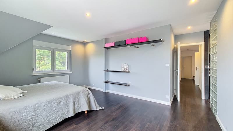 bedroom with wooden floors, bed, pillows, shelves, window with curtains, small radiator