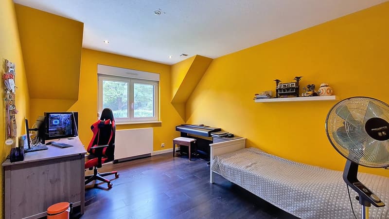 work area with desk, computer monitor, chair, small desk, single bed, piano, fan, radiator, stool, yellow walls, window