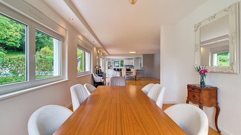 large table with 8 chairs, wooden flooring, large windows, flower vase, dining table in another room, kitchen table