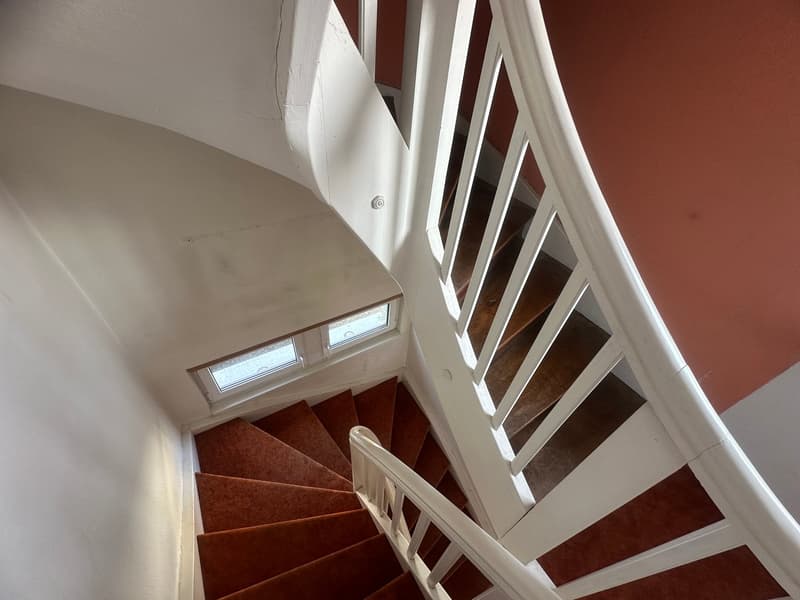 spiral stairs with wooden steps, white railing, windows on the stairs