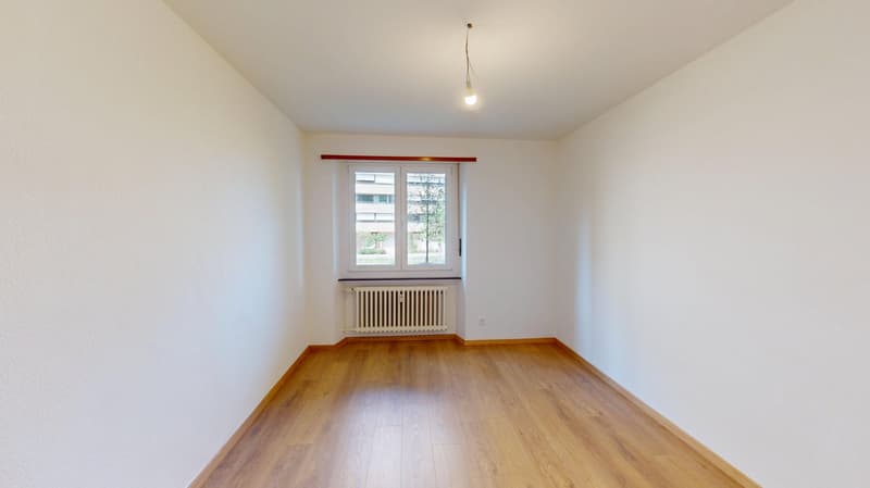 Empty room with white walls, hardwood floors, and a window.