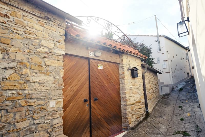 stone wall, double wooden doors, tiled roof, wall lamp, street lamp
