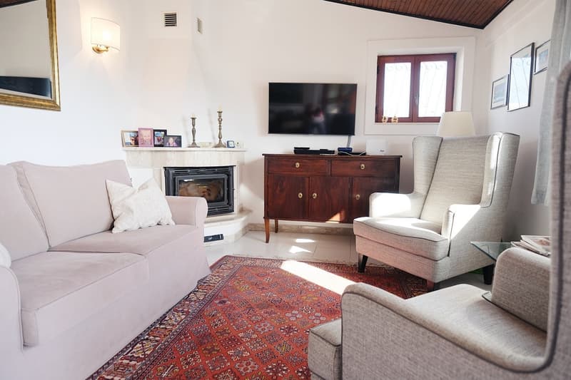white couch, carpet, TV, fireplace, wooden cabinet, arm chair, coffee table, picture frames