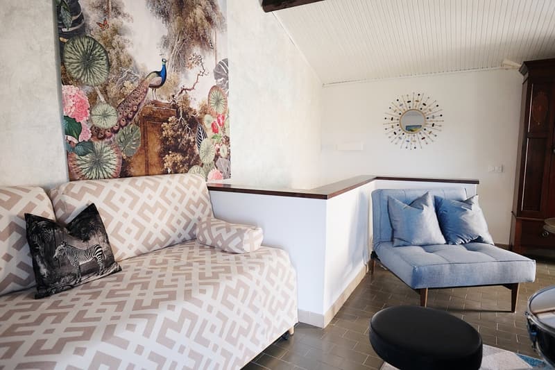 Geometric print sofa, peacock print wall art, decorative cushions, chaise lounge, mirror, round stool