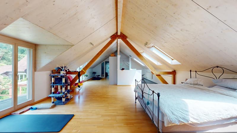 large wooden bed, beige wooden floors, large windows, skylights, blue yoga mat