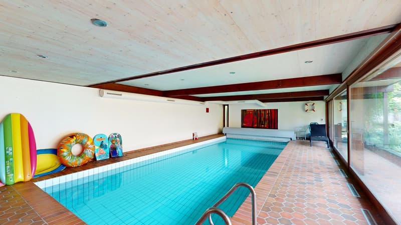 Large indoor swimming pool, white tiles, blue water, safety rail, inflatable toys