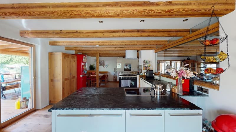 wooden beams, black marble countertop, white cabinets, stainless steel sink, red refrigerator, window with view of outside, wooden floor