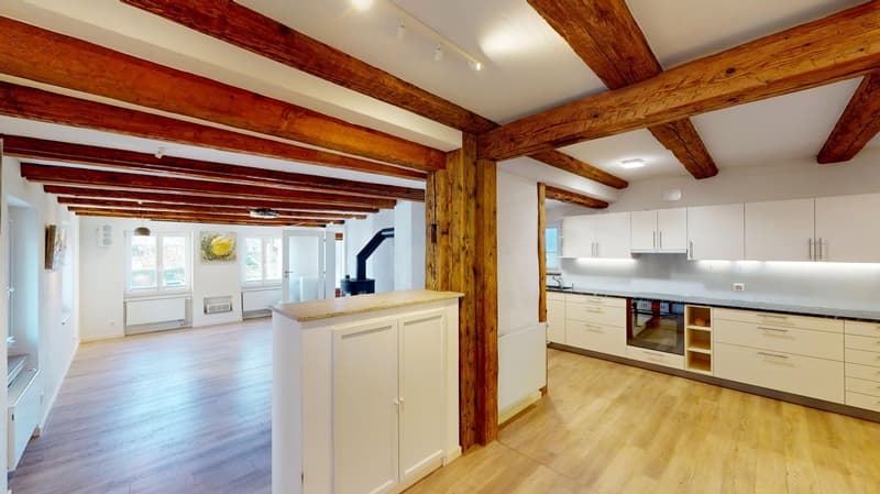 Open floor plan, wood beams, wooden floor, white cabinets, modern appliances, radiator