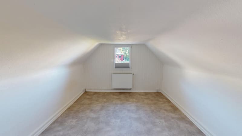 empty room with a sloping ceiling, window, and radiator